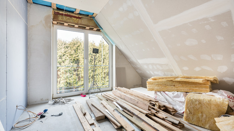 An empty room under construction with an angled ceiling and glass sliding doors