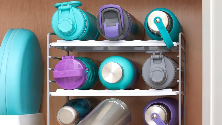 stacked multi-colored water bottles on a white rack in cabinet