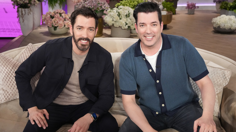 Drew and Jonathan Scott sitting on couch, smiling at camera