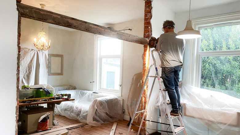 A construction worker removing a wall in a home.