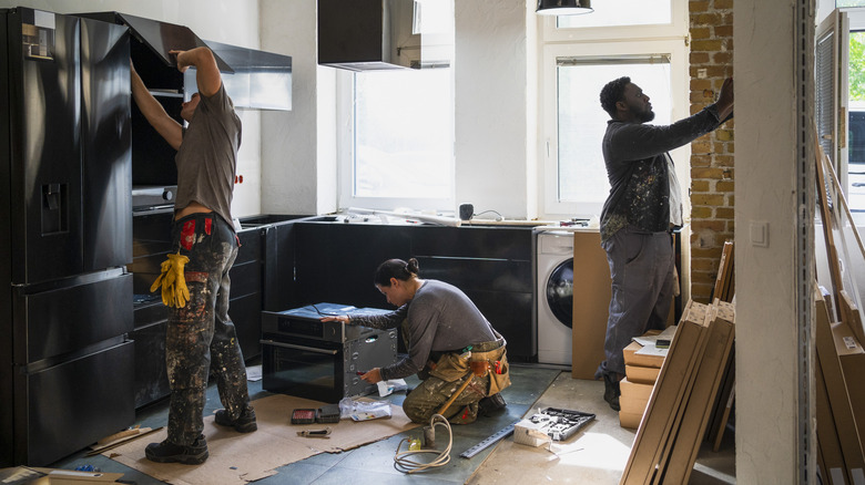 three workers renovating a kitchen