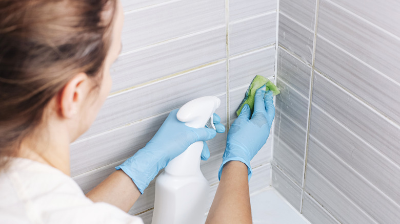 Woman cleaning grout in bathroom