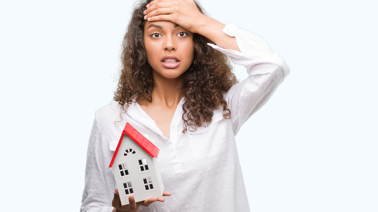 stressed woman holding small house