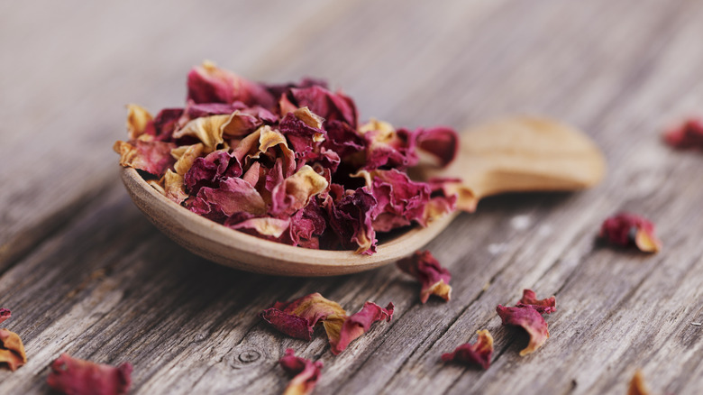 Wooden spoon filled with dry rose petals