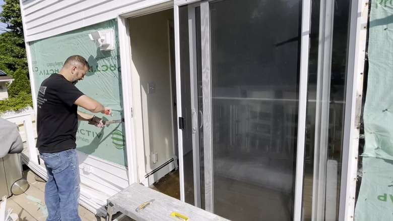 a man taking off the trim before replacing a sliding glass door