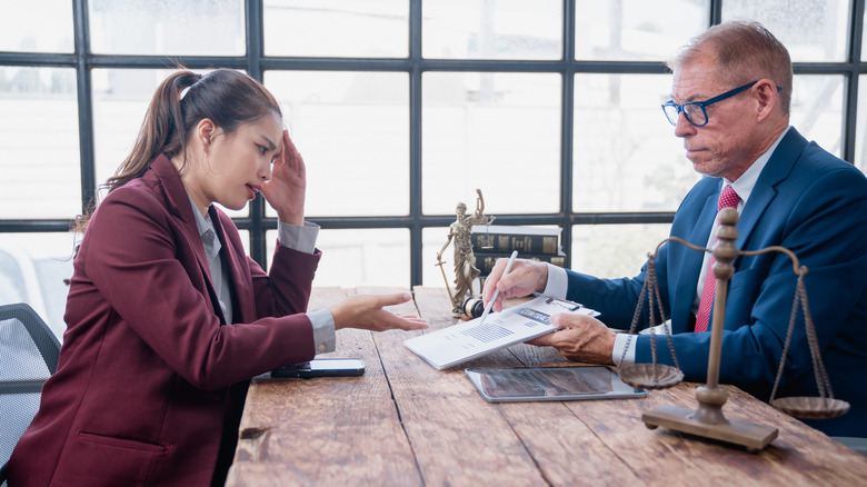 A well-dressed woman looks stressed as she speaks with her male lawyer.