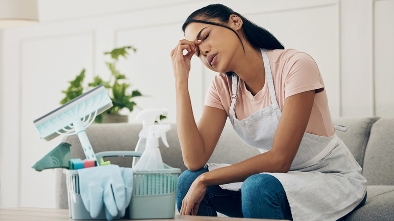 Woman with a headache takes a break from cleaning.