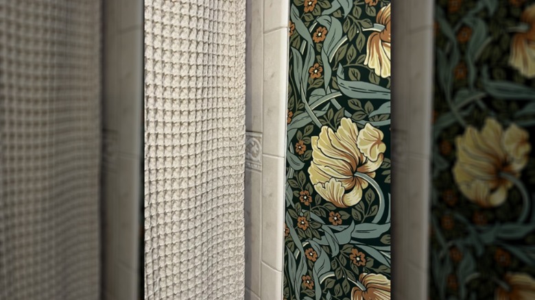 Bold art-deco wallpaper is complemented by a cream colored woven shower curtain.
