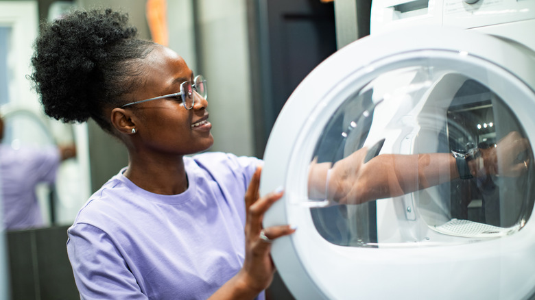 Woman using washing machine in laundry room