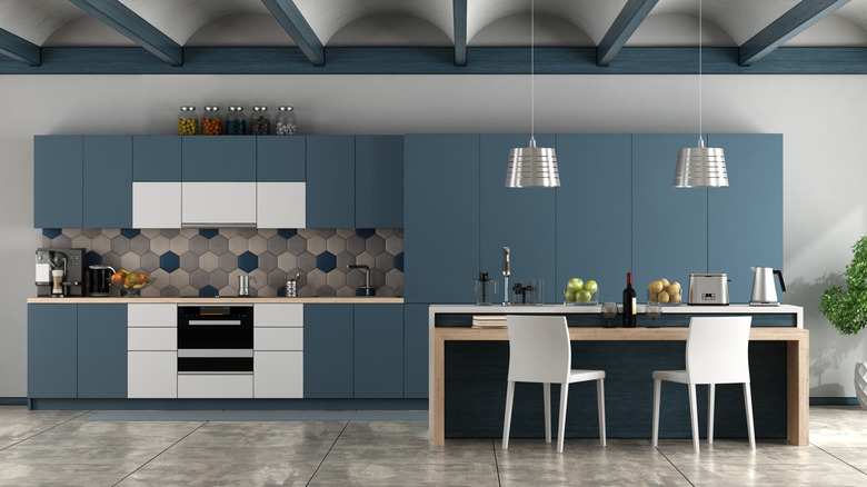 A minimalist kitchen with blue-grey cabinets and a table.