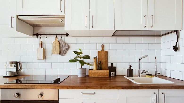 Simple, minimalist kitchen. White subway tile backsplash, wood countertop, white cabinetry, and electric stove.