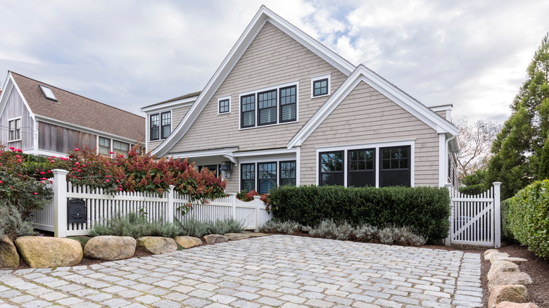 A beige house with gray driveway pavers