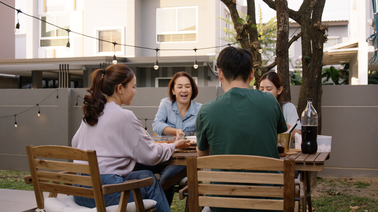 A family sitting in their front yard with string lights.
