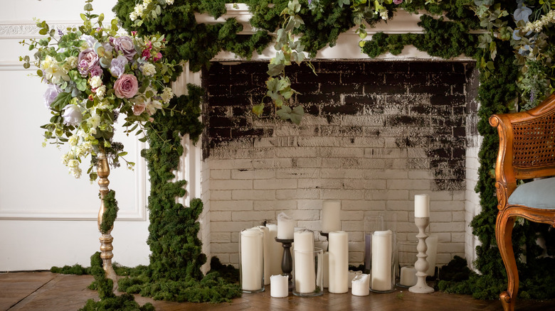 Fireplace full of candles and greenery