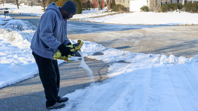A man pouring pellets to remove ice from the street