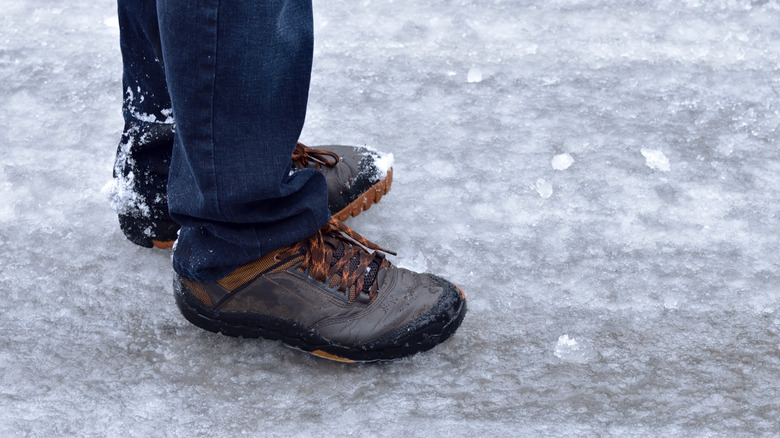 A man stands on top of a sheet of ice that has covered the street