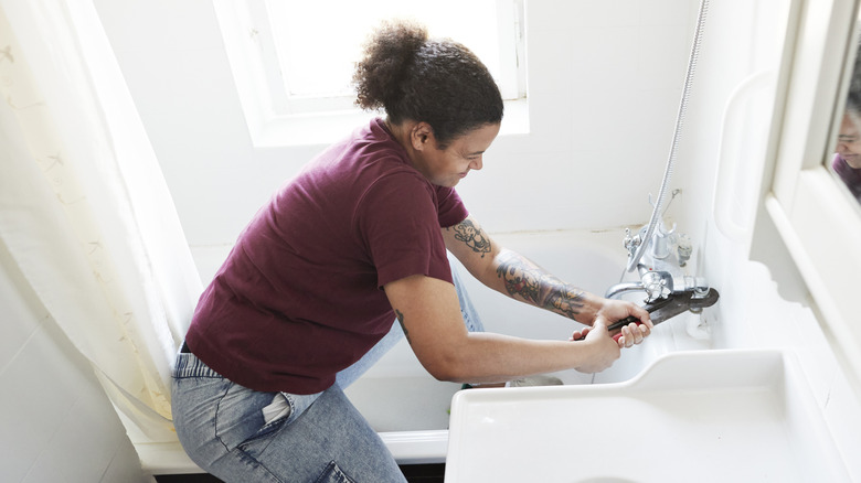 young woman performing renovations on a bathroom faucet