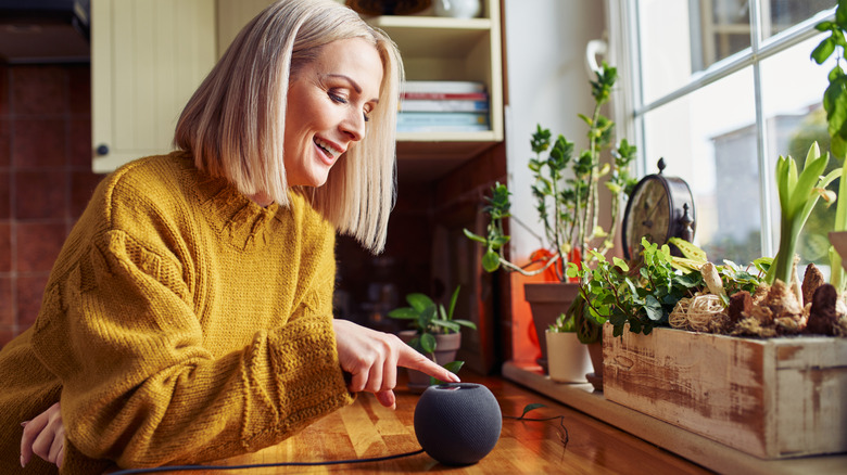 A woman using a smart speaker in a kitchen