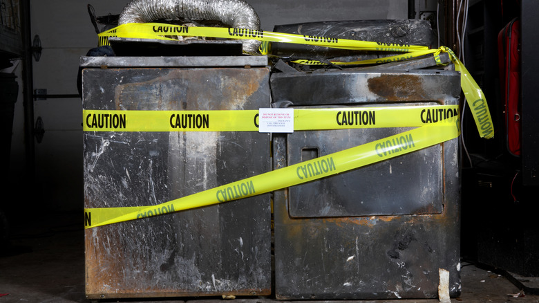 A burnt washer and dryer surrounded by yellow caution tape