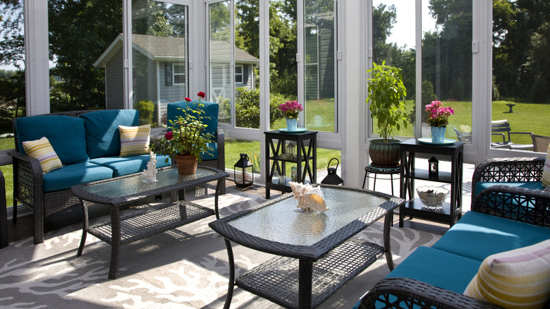 Rattan furniture in a three-season room with view of yard and shed
