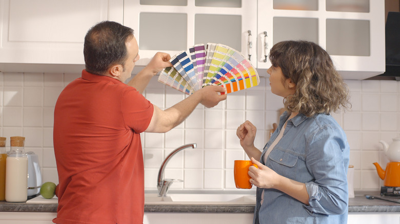 Couple choosing paint for kitchen