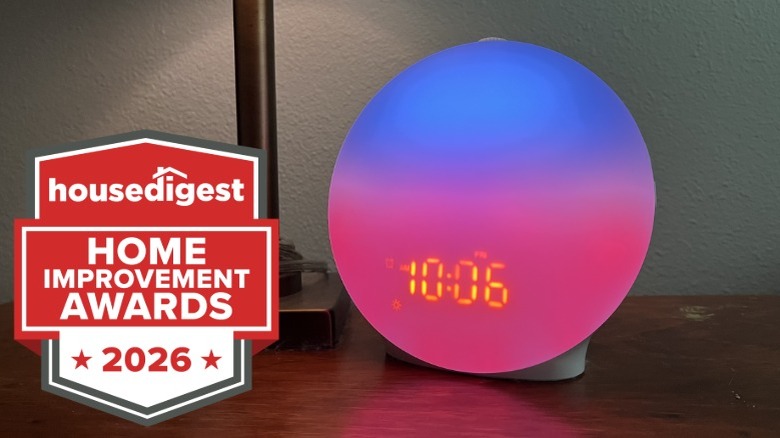 A sunrise alarm clock sitting on a nightstand showing the time 10:06
