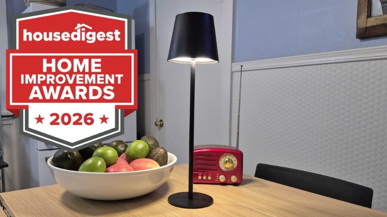 A black cordless lamp on a kitchen table next to a fruit bowl and a radio