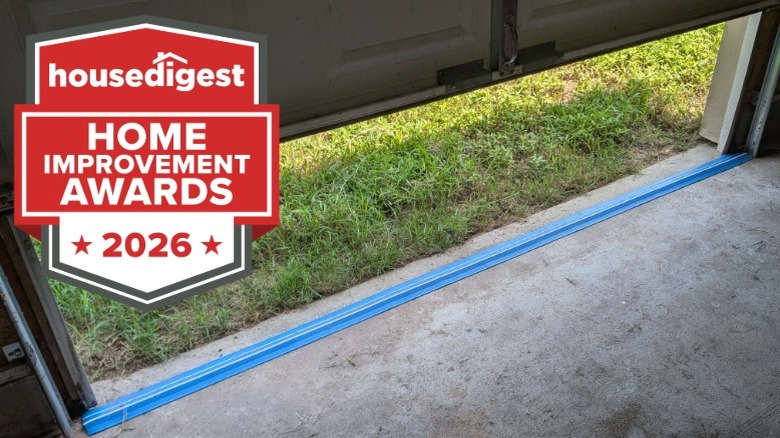 A blue garage door seal strip on a concrete floor near grass