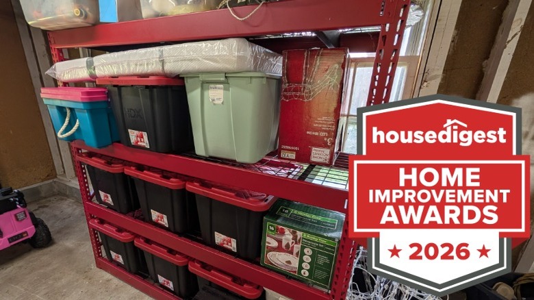 A red shelf in a garage holding plastic bins and boxes