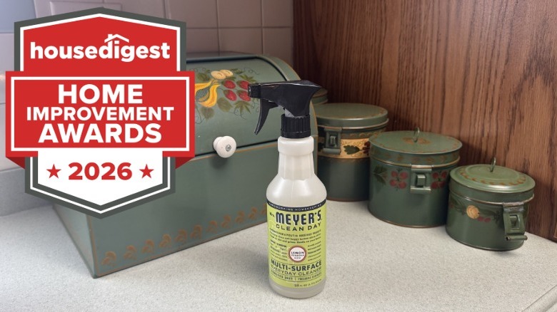 A bottle of Mrs. Meyer's Clean Day cleaner on a countertop next to green canisters