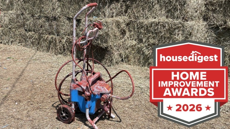 A paint sprayer in front of bales of hay outdoors