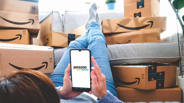 Woman shopping on Amazon Prime on her phone with boxes surrounding her