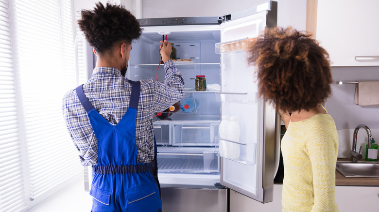 A person looking at a broken refrigerator