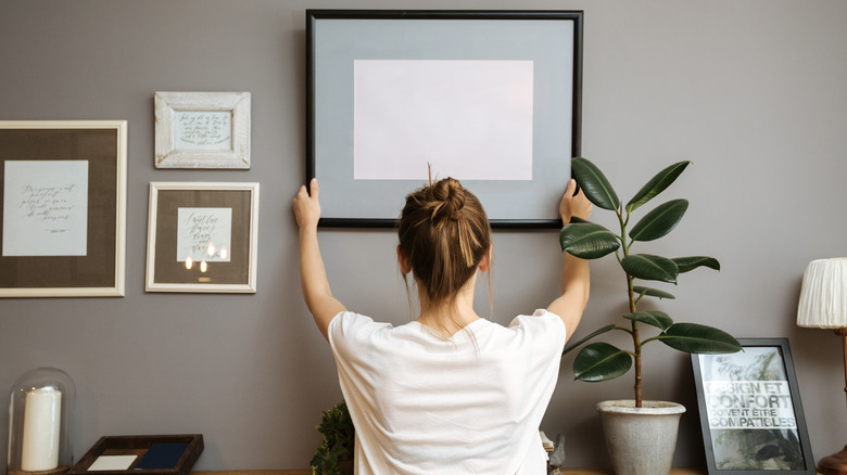 Person decorating wall with frame