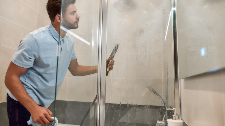man steam cleaning shower