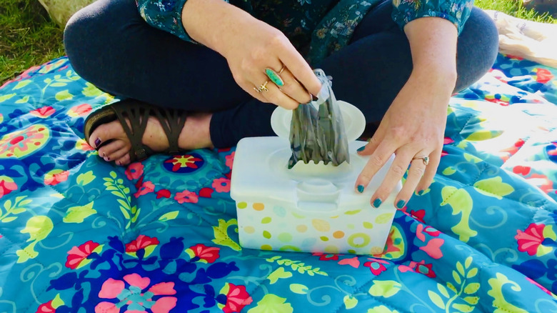 Woman pulls a plastic bag from a baby wipes container.