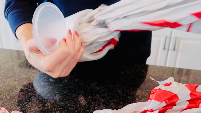 Woman pulls plastic bags from cleaning wipes container.