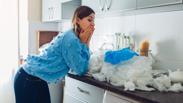 A woman overwhelmed with the pile of plastic bags in her kitchen