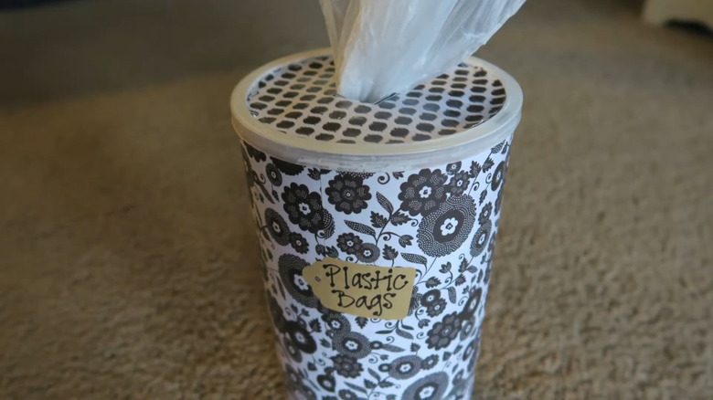 An oatmeal container repurposed into plastic-bag storage.