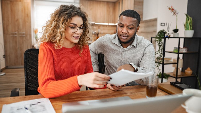 A couple sits together at a desk while doing paperwork
