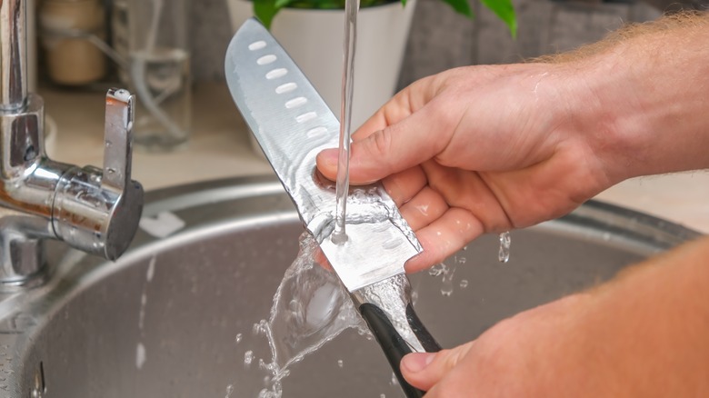 Person washing kitchen knife