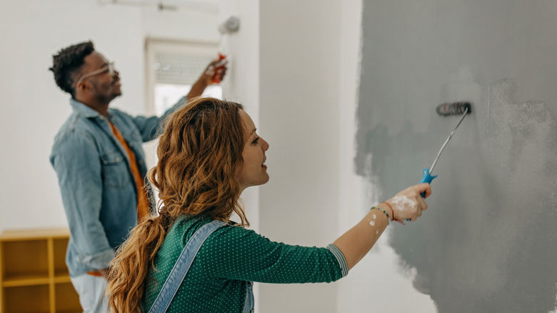 couple painting wall with rollers