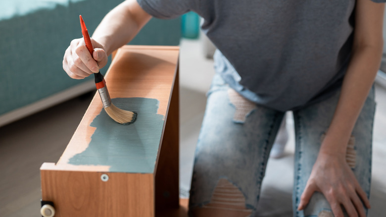 Person painting a furniture drawer with green paint