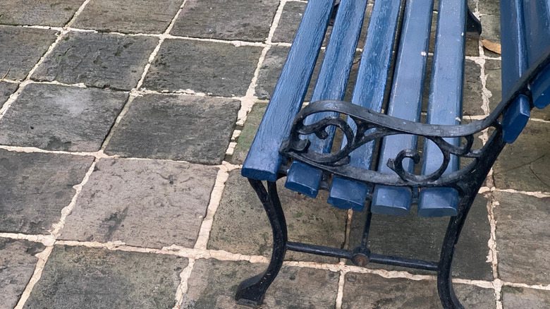 An outdoor bench made of metal and wood painted blue