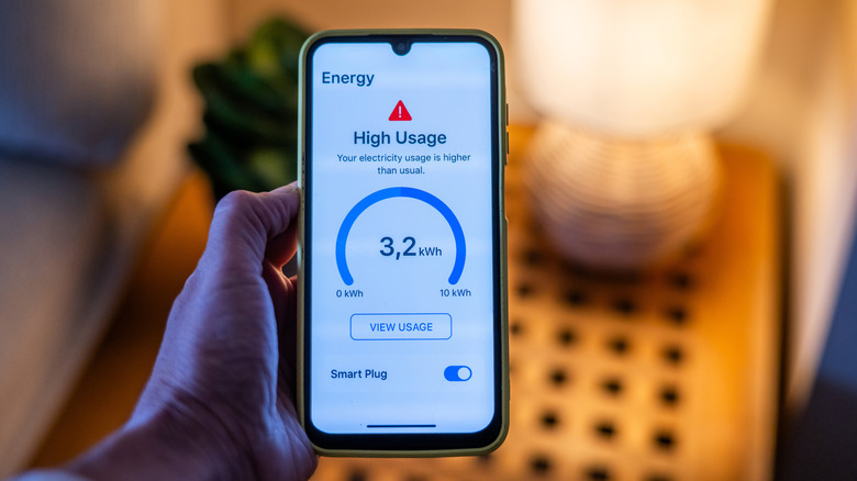 Person checking high energy usage alert from the smart plug on the phone