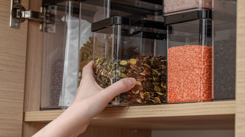Hand reaching for container on pantry shelf