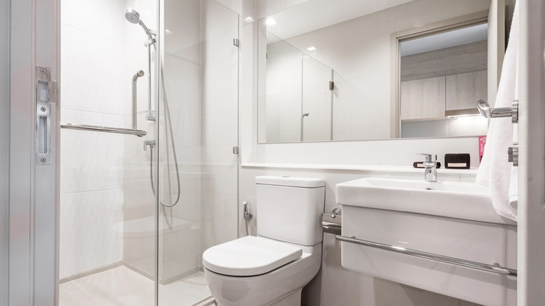 An all-white modern bathroom with a sink, toilet, and walk-in shower
