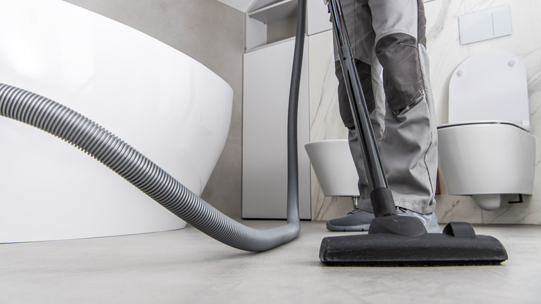 Person vacuuming bathroom floor