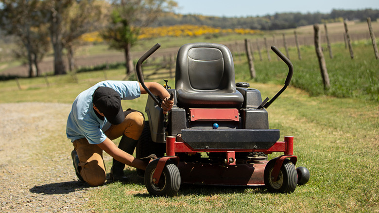 Man checking the blades on the riding mower deck