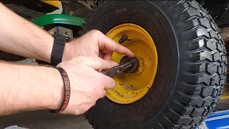 Someone replacing the tire of a lawn mower